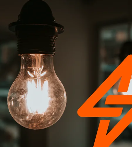 Vintage filament bulb glowing warm white in black holder with large orange Safehouse double bolt logo overlay right side